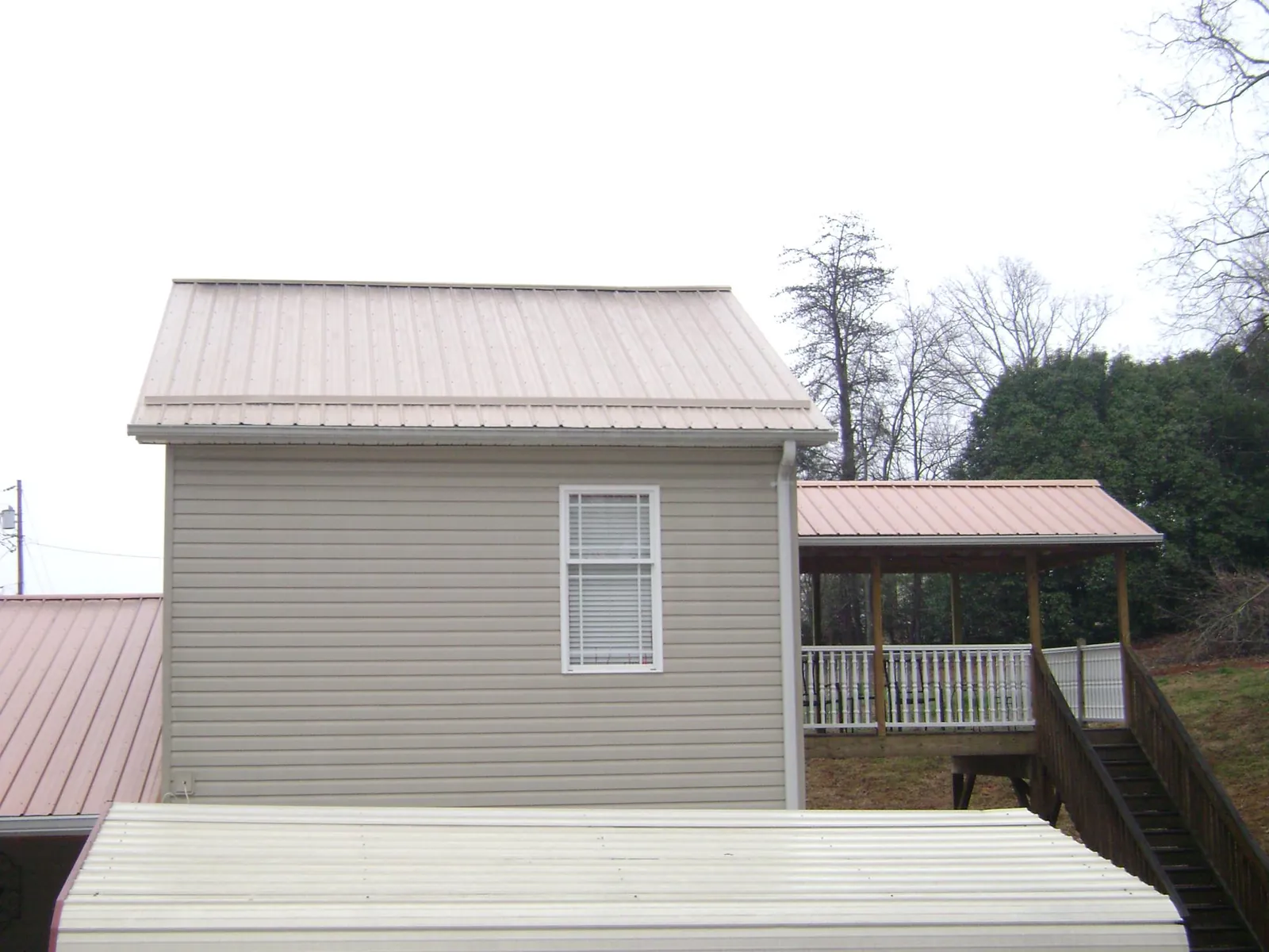 Tan metal roofs on a two story addition and attached porch, from a Roof Replacement job in Ephrata