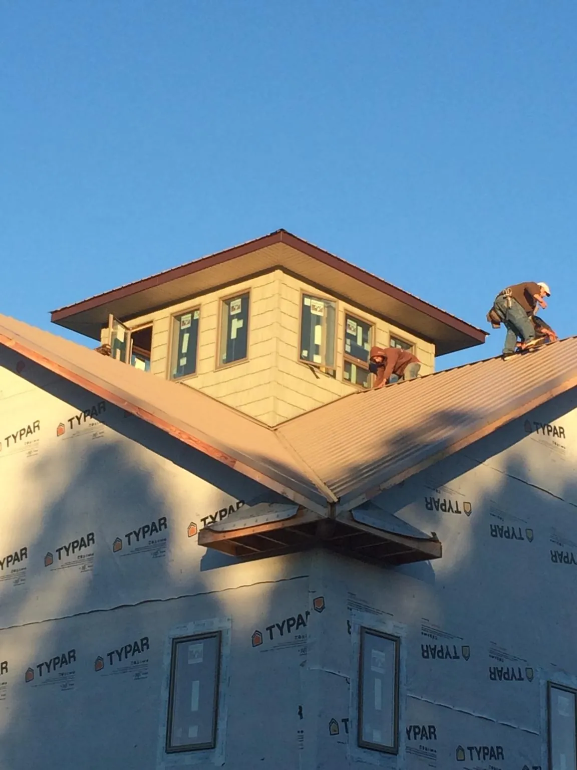 Roofers working around a rooftop cupola on a new metal roof at sunset — Roof Waterproofing in Ephrata by Roofing Brothers